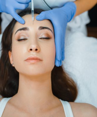Cosmetician gives face botox injections to patient